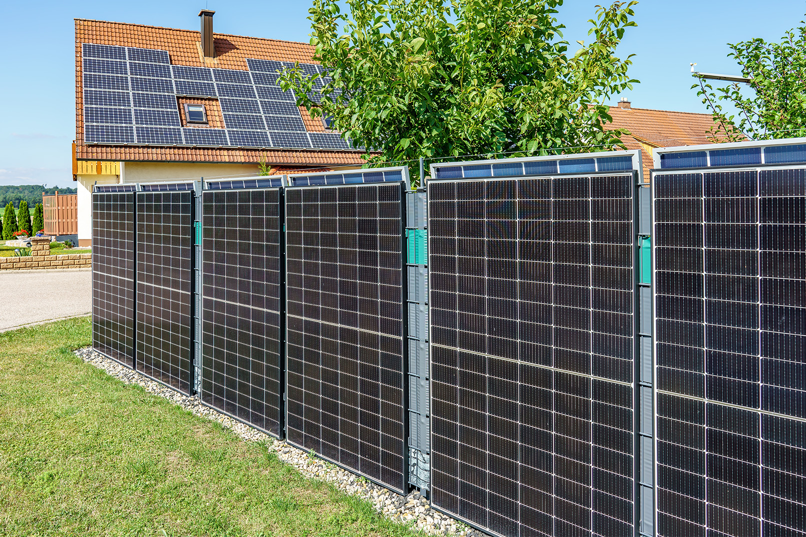 Solar panel fencing Solar panels line fence with house and solar panelled roof in background