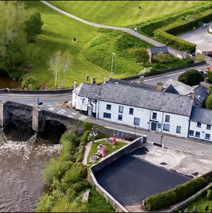 Aerial view of house next to filed and bridge over river