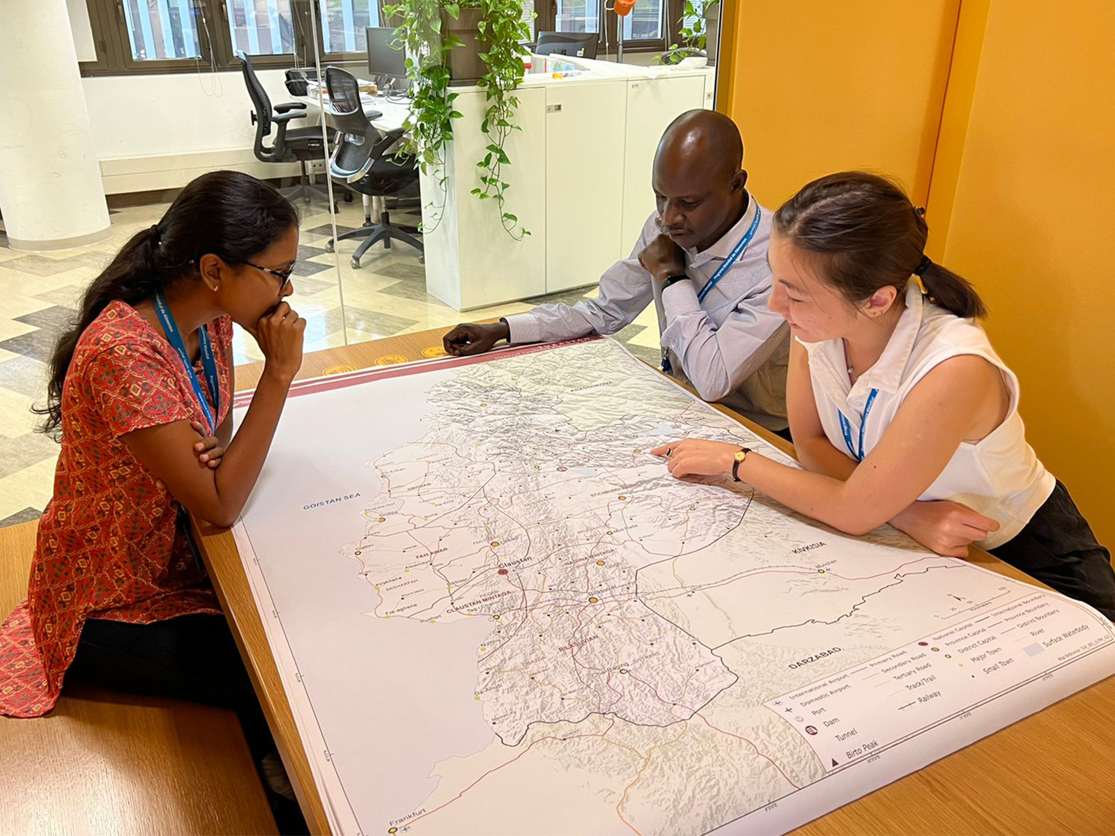 Three people sit around table looking at a map