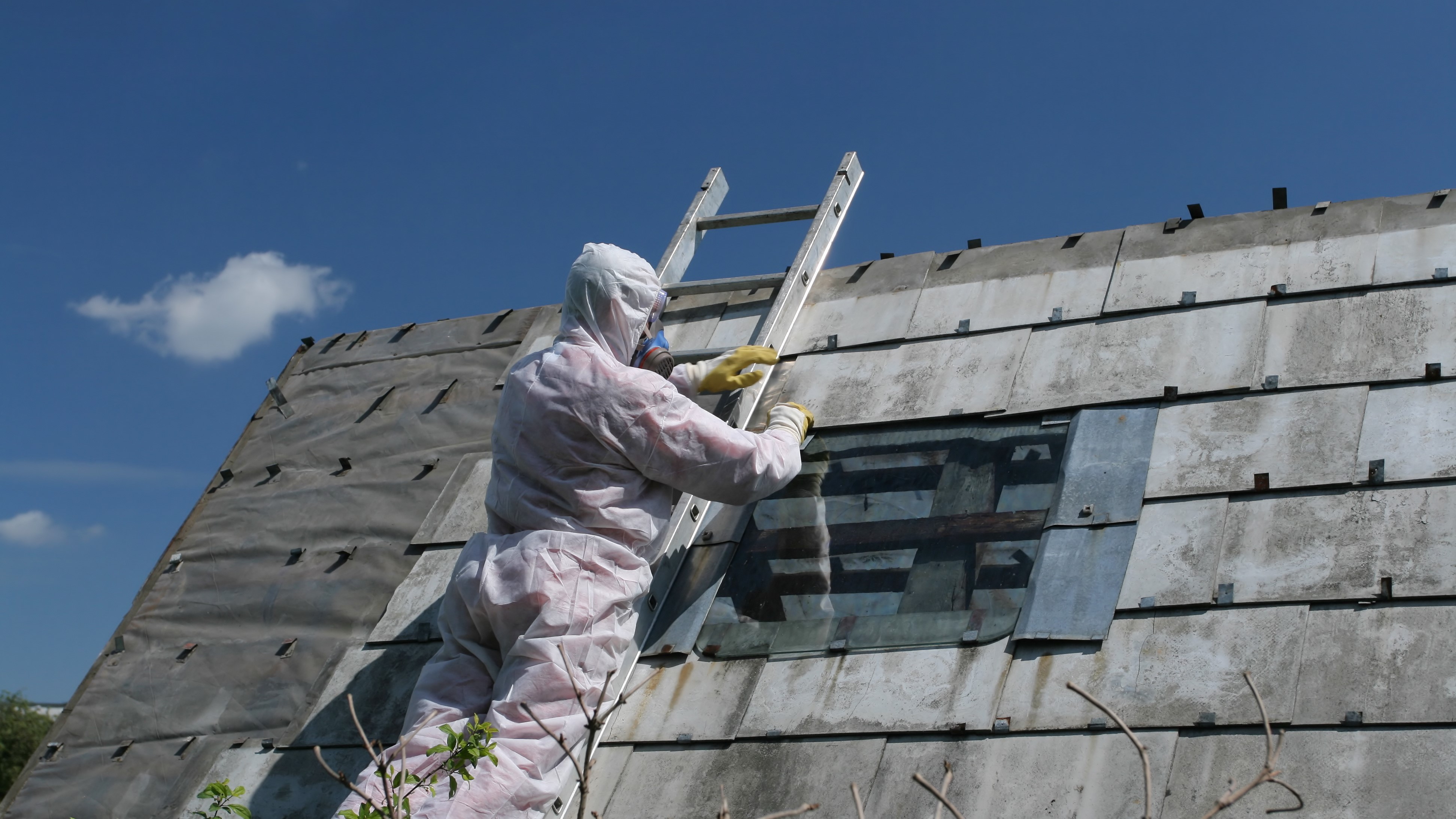 Worker removing asbestos from roof