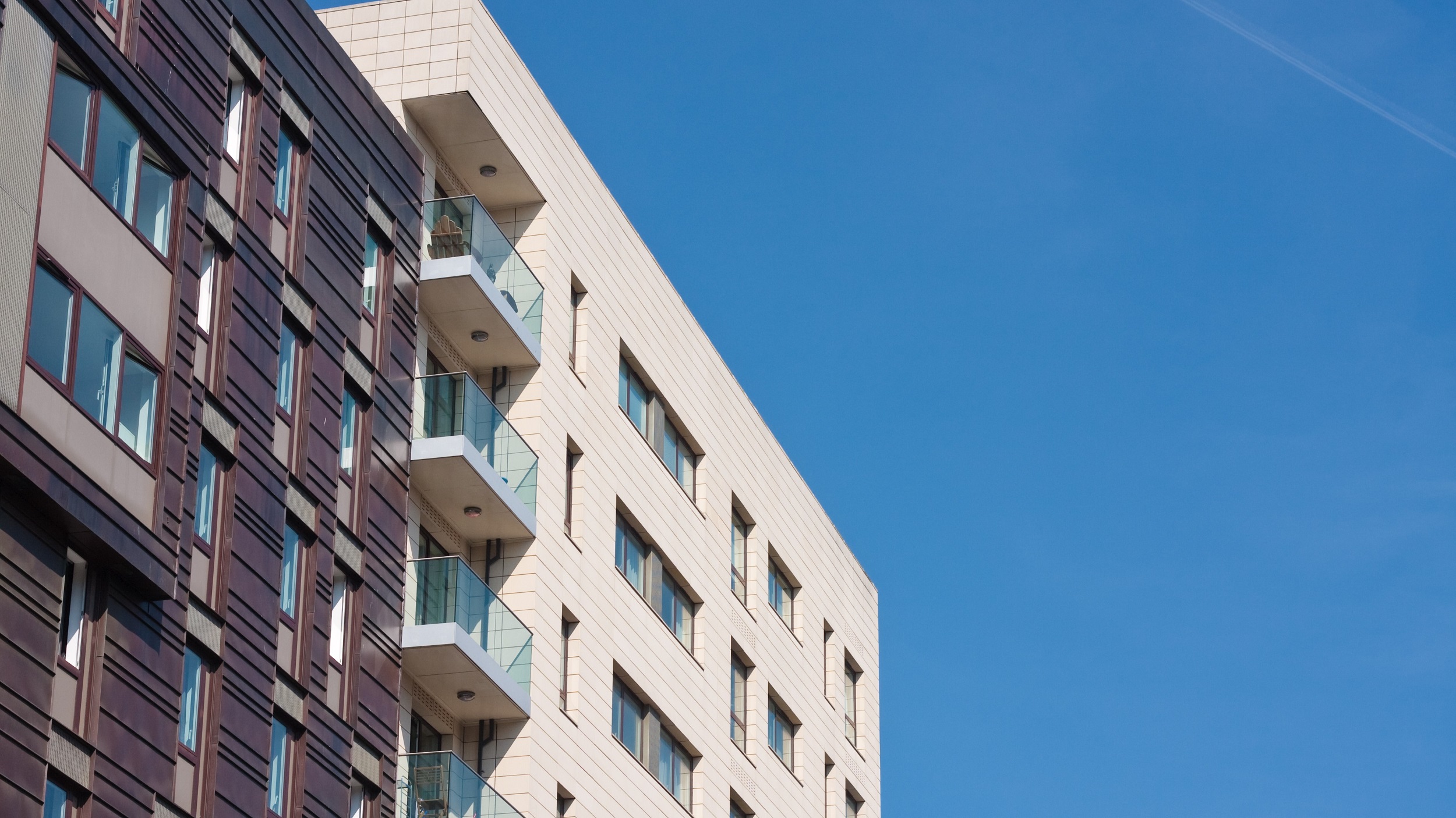 Block of flats against blue sky background