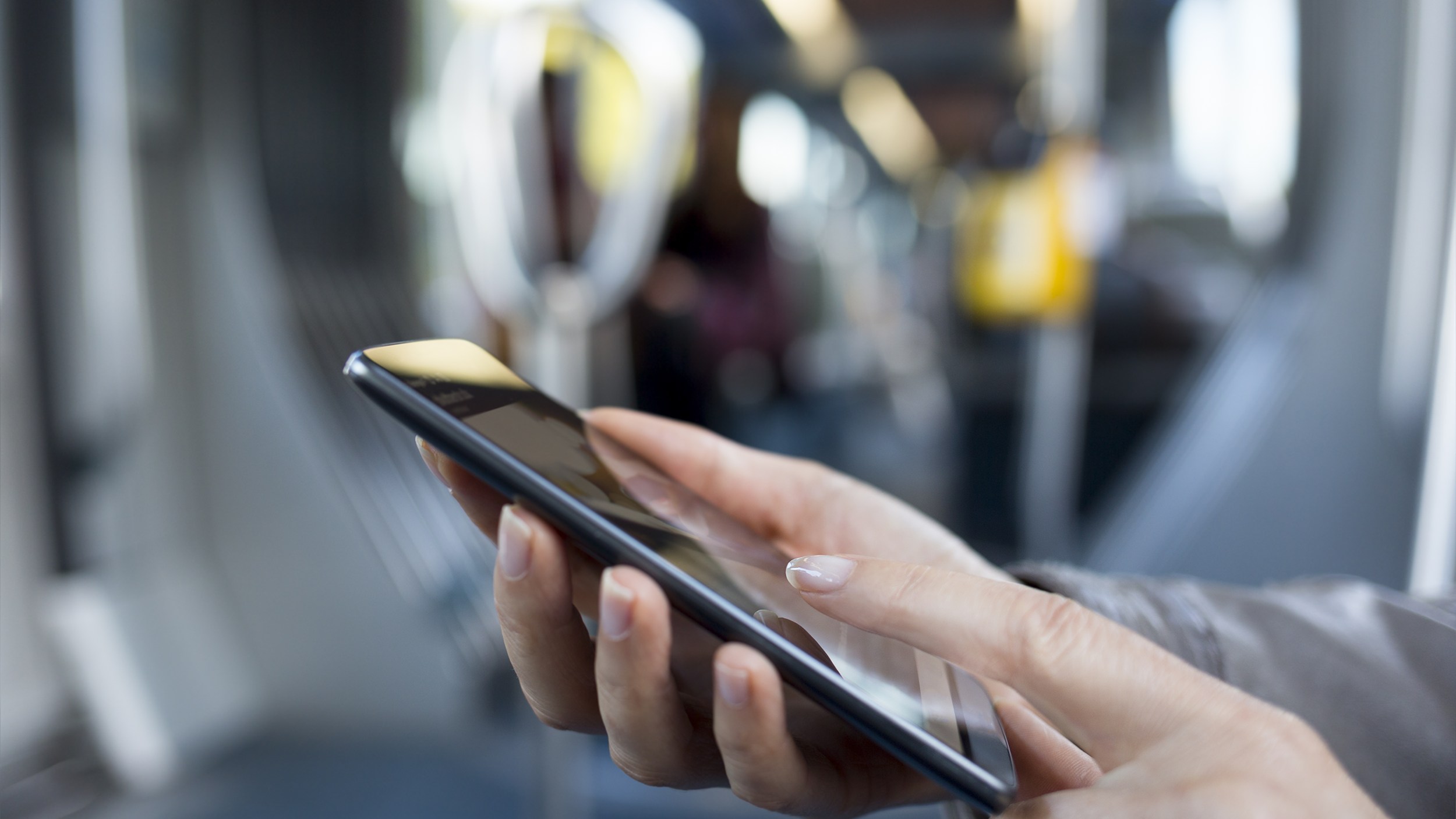 Woman's hands holding mobile phone in Underground carriage close-up