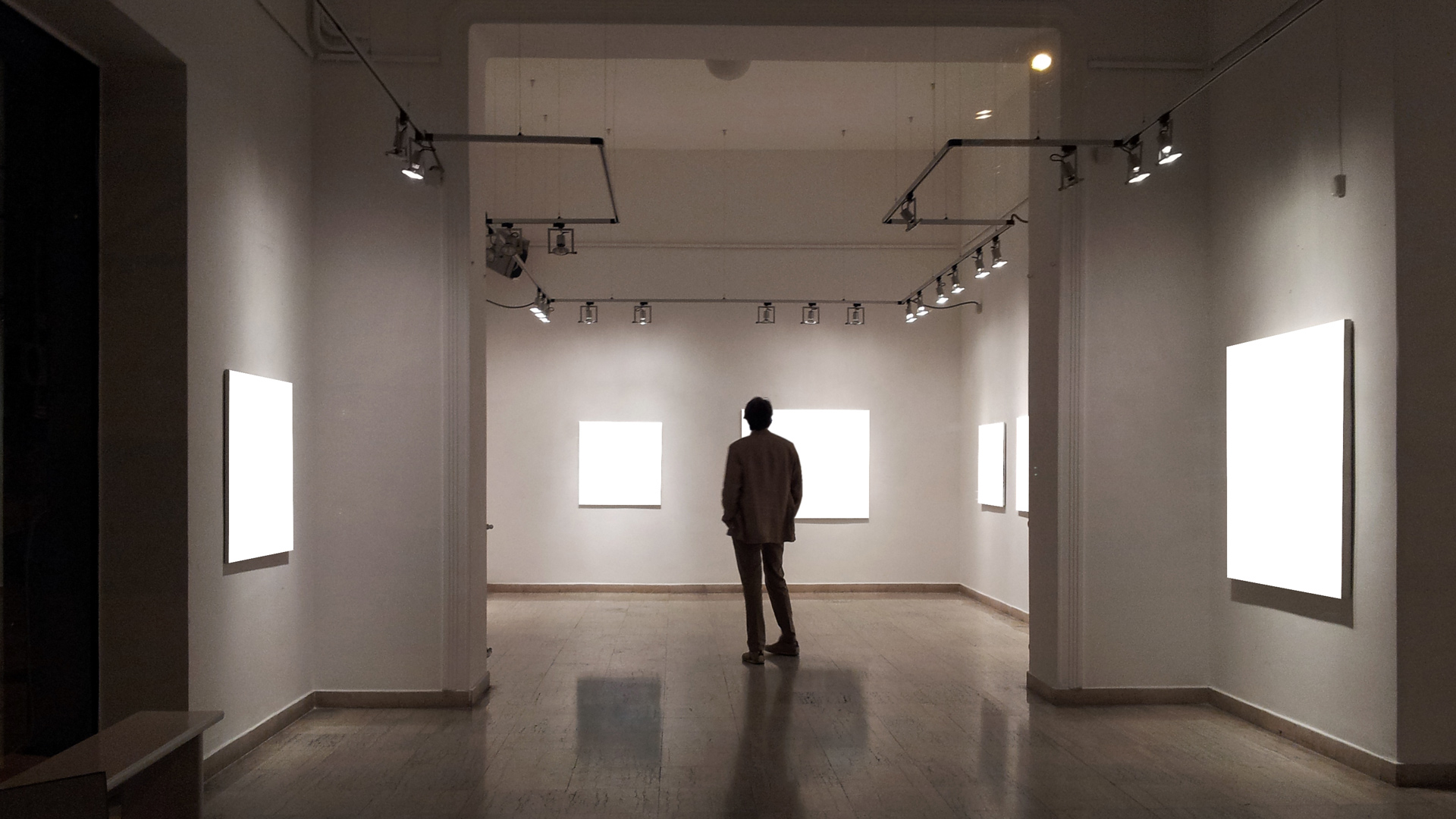 Man in shadow in darkened gallery with empty canvases