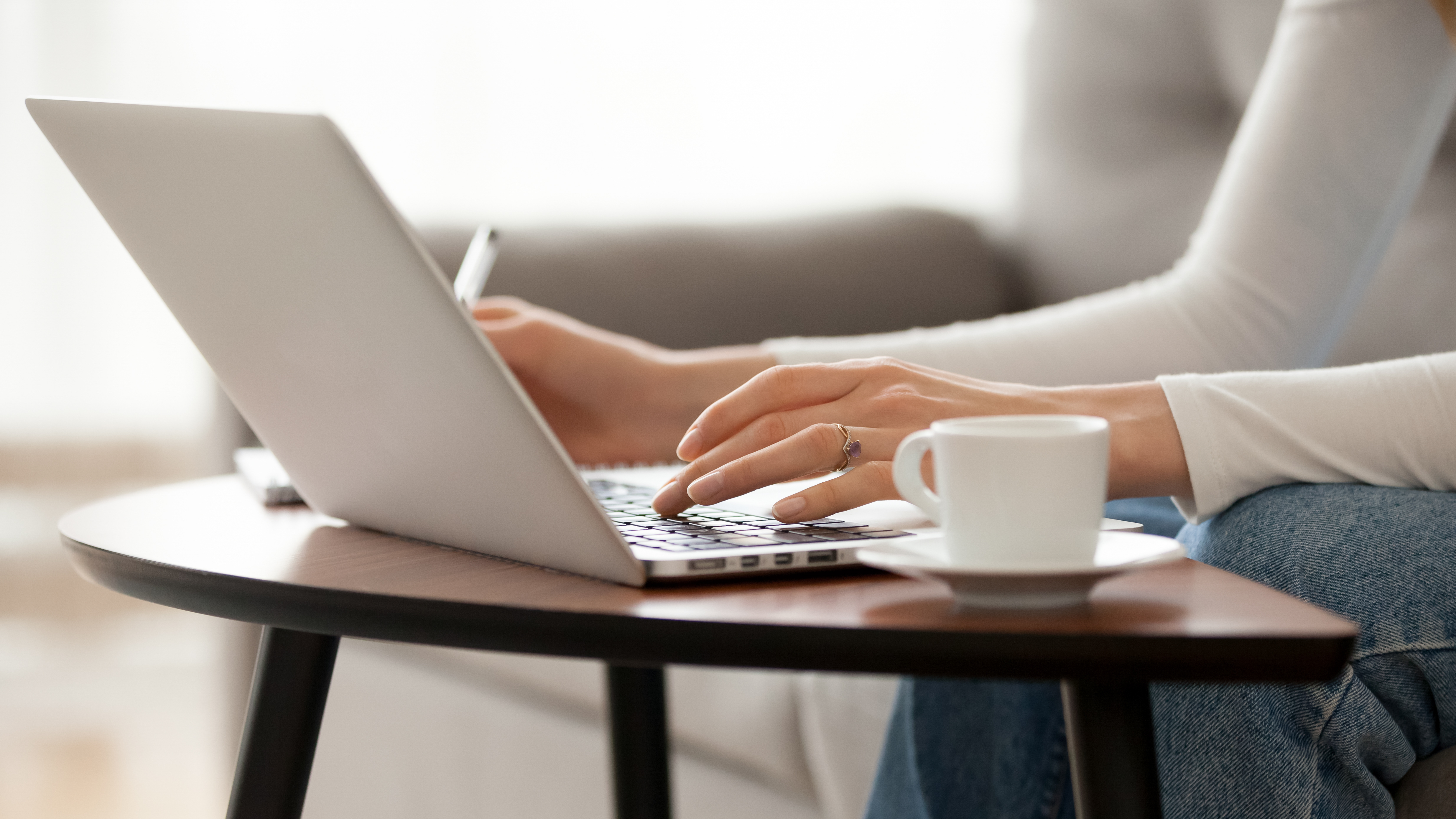 Close up woman using laptop, sitting on sofa, female hands typing, writing notes, studying languages, distance learning concept, checking email in morning, drink coffee, working at home; Shutterstock ID 1363683854; purchase_order: NA; job: Property Journal March 22; client: RICS; other: 