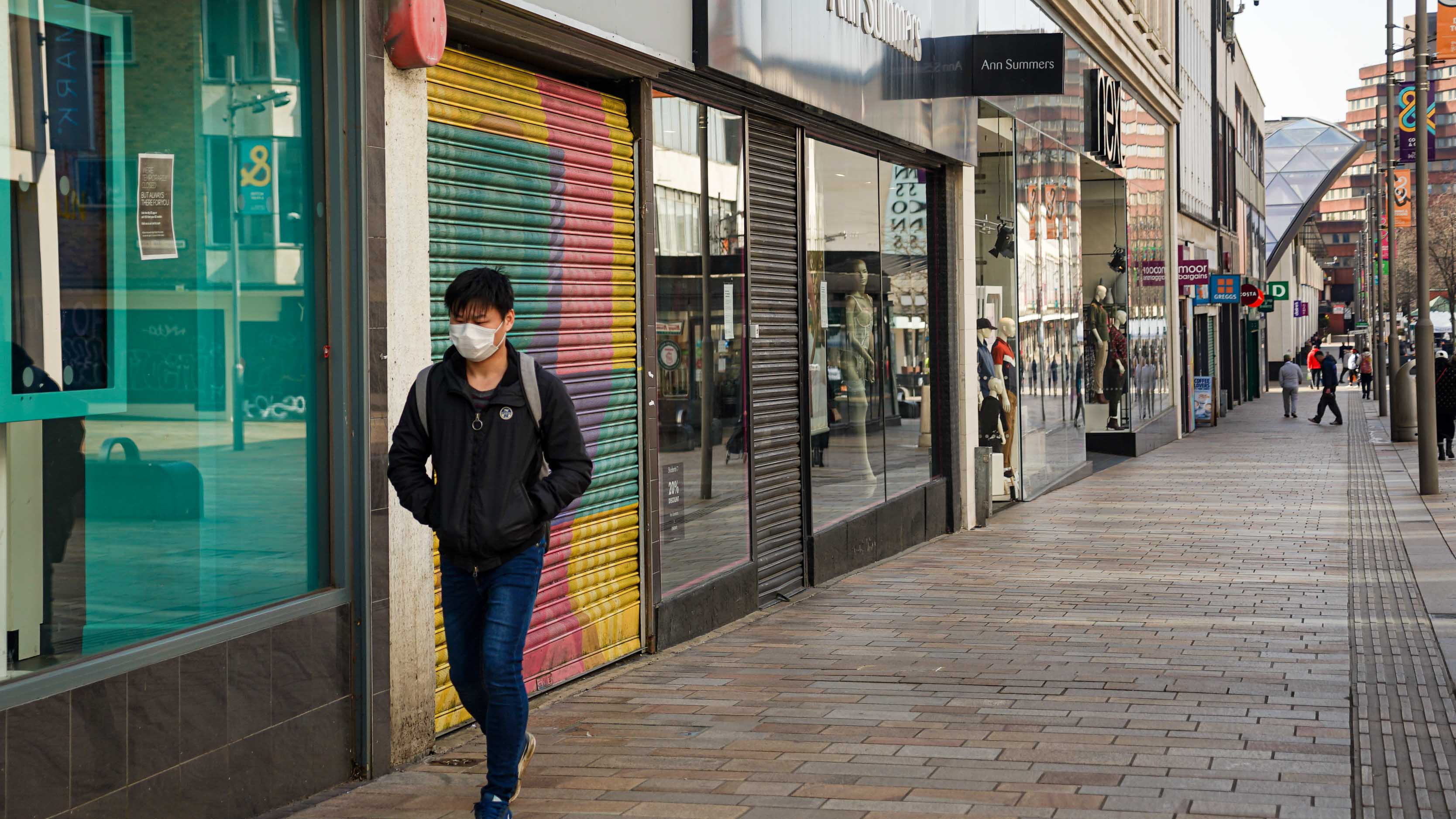 Sheffield, UK - March 24, 2020: A pedestrian wearing protective face mask while walking past closed shops on the first day of UK lockdown. Sparse street people in central Sheffield during the pandemic; Shutterstock ID 2036349635; purchase_order: NA; job: Property Journal May 22; client: RICS; other: 